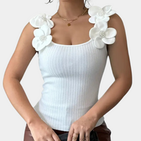 Frau in weißem, geripptem Tanktop mit Blumenapplikationen und Perlen, modisch, elegant.