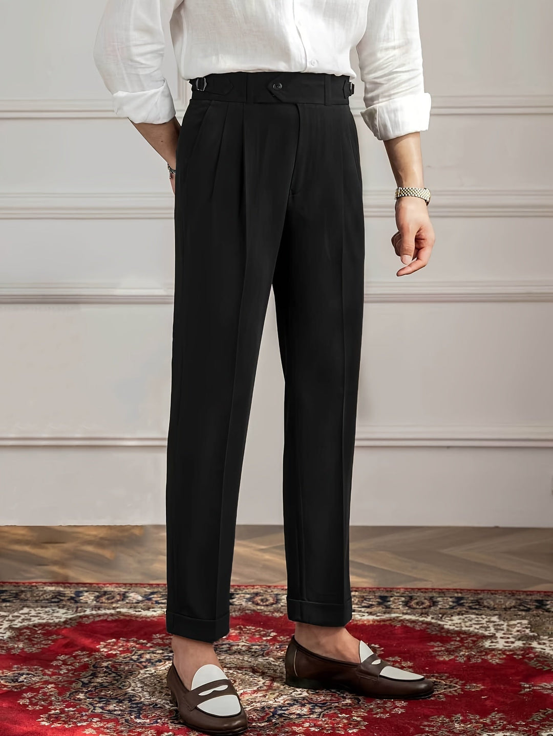 Mann in schwarzer Anzughose, weißem Hemd, braunen Loafers auf rotem Teppich.