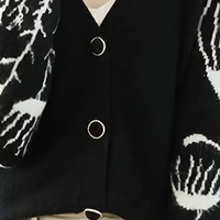 Schwarze Strickjacke mit weißen Mustern und Knöpfen, modische Damenbekleidung.