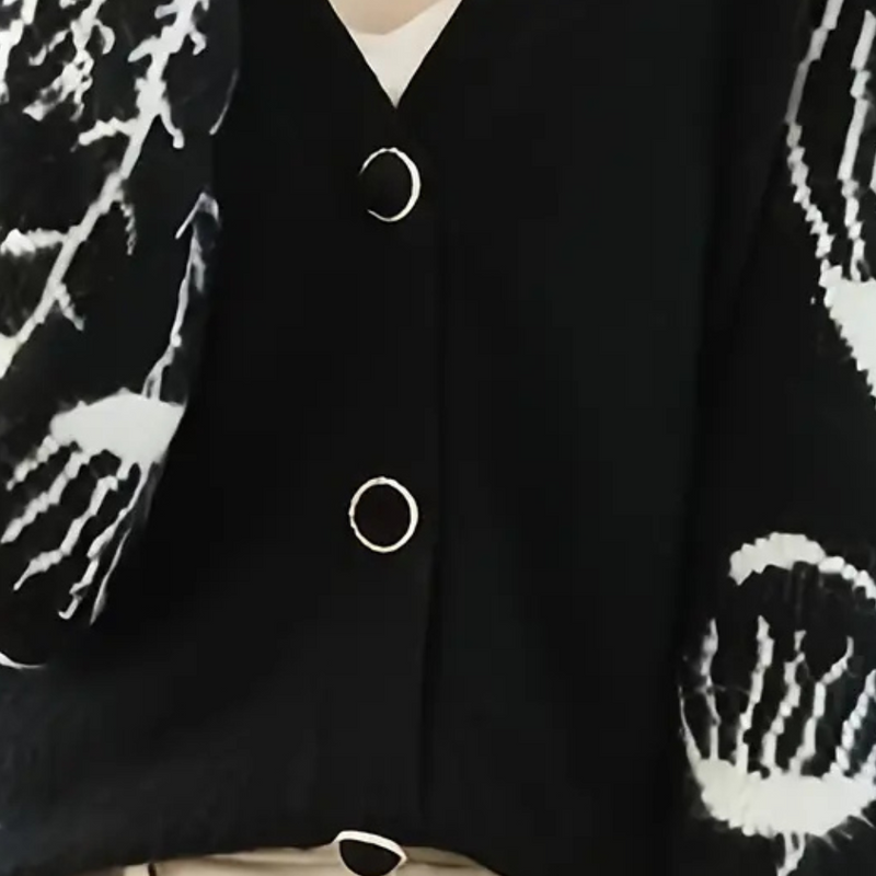 Schwarze Strickjacke mit weißen Mustern und Knöpfen, modische Damenbekleidung.