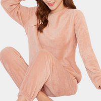 Frau in rosa Fleece-Pyjama-Set, gemütlich, langärmelig, ideal für kalte Nächte.