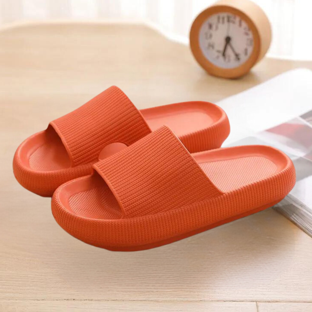 Orange Badeschlappen auf Holztisch, rutschfest, bequem, für Damen und Herren.