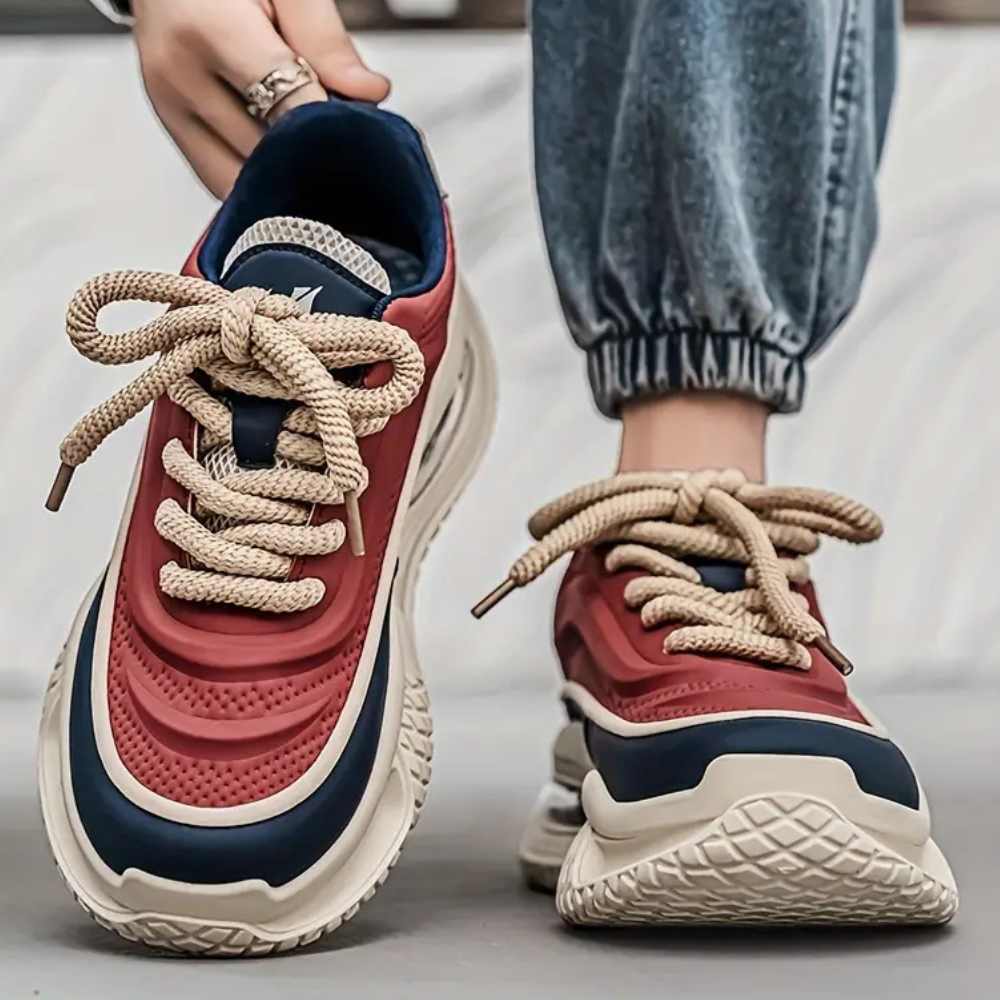 Rote und blaue Sneaker mit dicken Sohlen, beige Schnürsenkel, lässiger Streetwear-Stil.