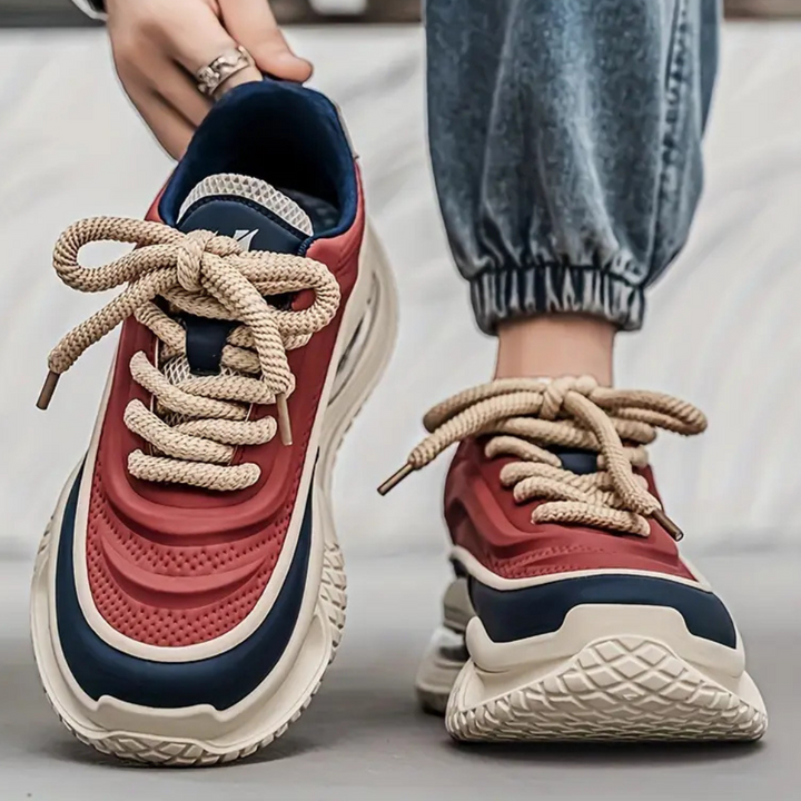 Rote und blaue Sneaker mit dicken Sohlen, beige Schnürsenkel, lässiger Streetwear-Stil.