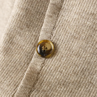 Beiger Strickstoff mit braunem Knopf, Nahaufnahme, Textur, Mode, Detailansicht.