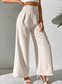 Frau in eleganter, weißer, hochtaillierter, weiter Hose aus Baumwolle, Sommermode.