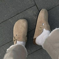 Beige Wildleder-Clogs mit Schnalle, getragen auf grauem Pflaster, modische Herrenschuhe.