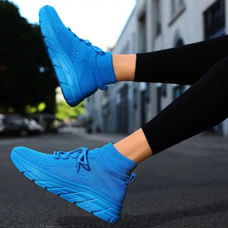 Blaue Sportschuhe, gestricktes Material, Straßenhintergrund, bequeme Laufschuhe, Damenmode.