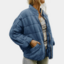 Frau in blauer Steppjacke, Reißverschluss, lässig, modisch, Herbstkleidung, Damenmode.