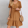 Frau in braunem Sommerkleid mit Strohtasche, modisch, lässig, Damenmode, Boho-Stil.