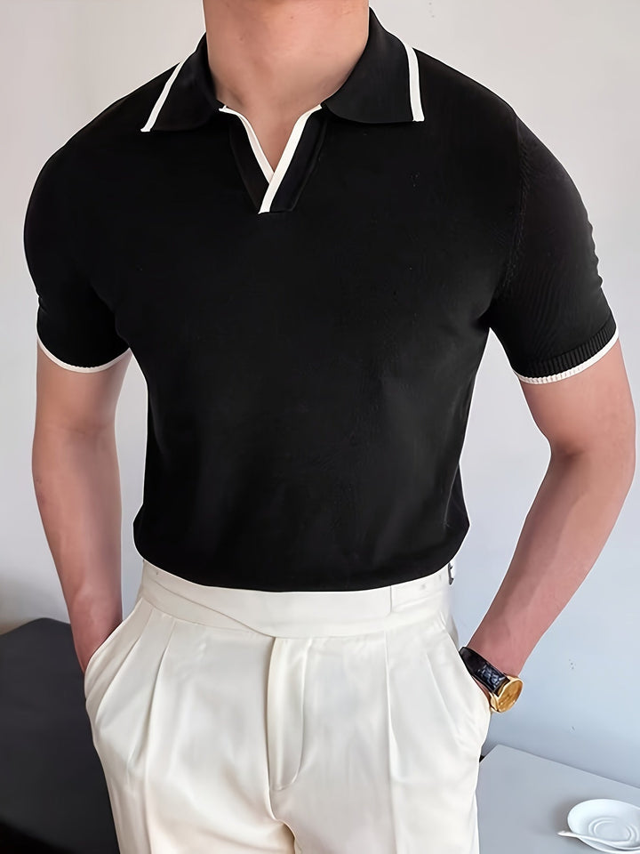 Mann in schwarzem Polohemd mit weißen Details und weißer Hose, eleganter Freizeitlook.