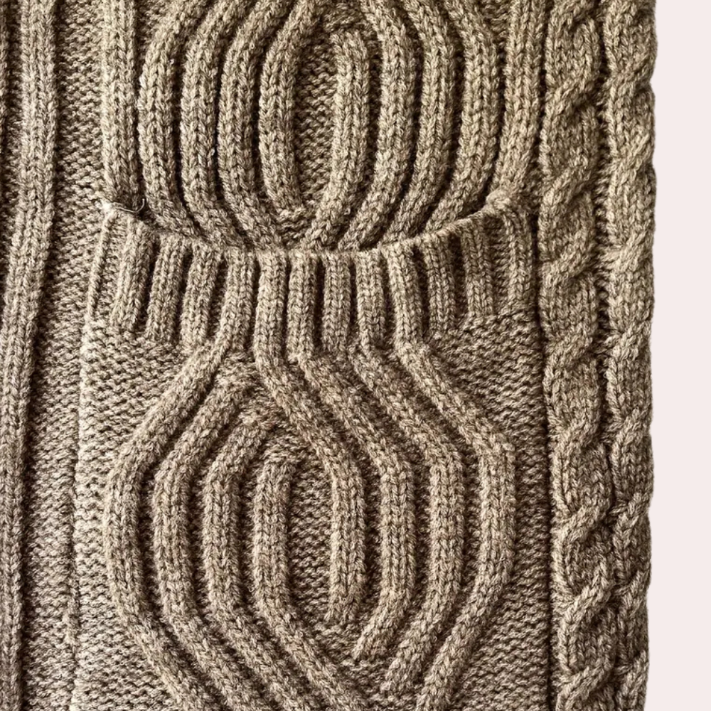 Braunes Strickmuster aus Wolle mit Zopfmuster, geometrischen Formen, handgefertigt, Detailansicht.