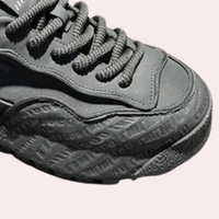 Schwarzer Sneaker mit geprägter Sohle, sportliches Design, Nahaufnahme, modisch, Unisex.