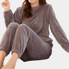 Frau in grauem Fleece-Pyjama-Set, gemütliche Winterkleidung, weiches Material.