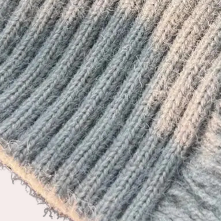 Grauer Strickstoff, Nahaufnahme, weiche Textur, geripptes Muster, hochwertige Wolle.