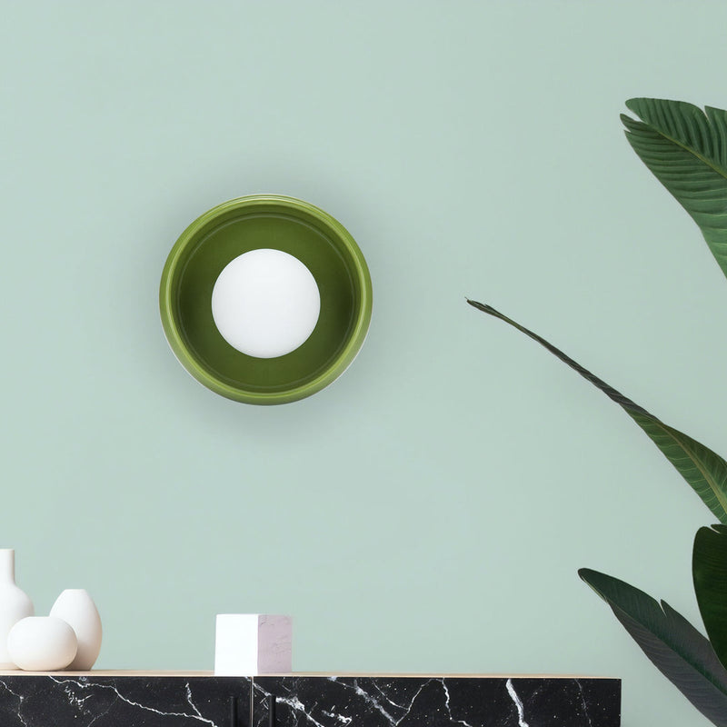 Grüne Wandleuchte mit rundem Design auf mintgrüner Wand, moderne Innenbeleuchtung.