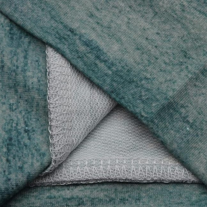 Grüner Stoff mit weißem Netzfutter, Nahaufnahme, Textilstruktur, Nähte sichtbar.