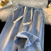 Hellblaue Jogginghose aus Denim mit Kordelzug, lässig, bequem, modisch, auf flauschigem Teppich.