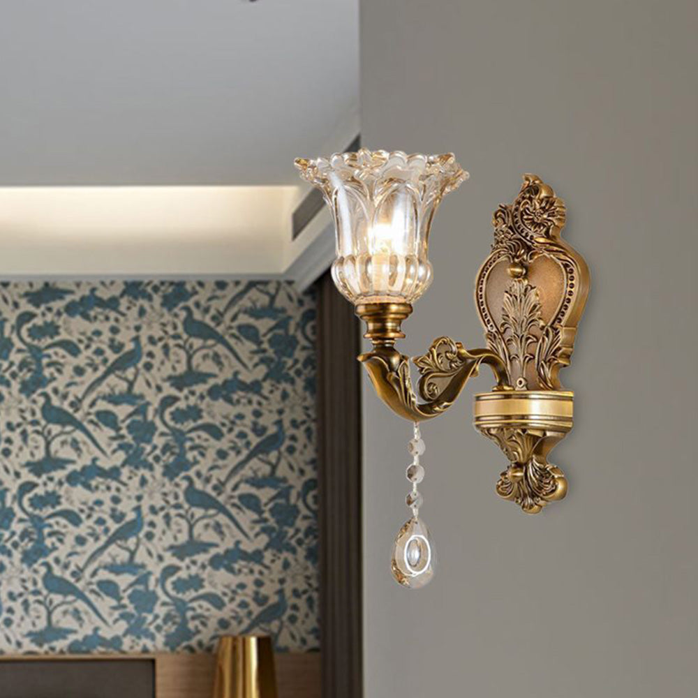 Klassische goldene Wandleuchte mit Glaslampenschirm im Vintage-Stil an grauer Wand.