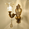 Klassische goldene Vintage-Wandleuchte mit Glaslampenschirm und dekorativem Kristallanhänger.