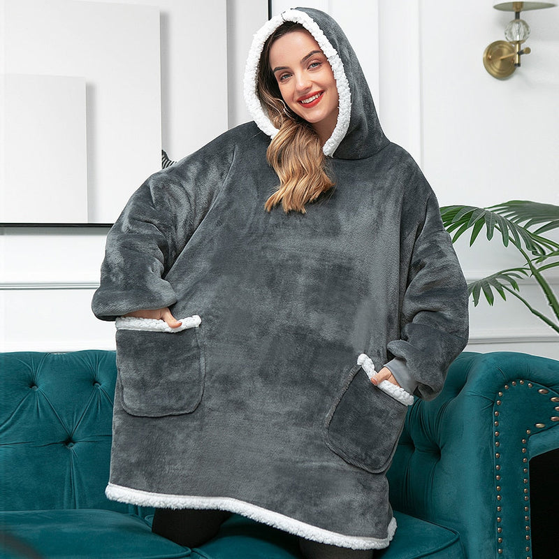 Frau in grauem, flauschigem Oversize-Hoodie mit Kapuze und Taschen, gemütliche Winterkleidung.
