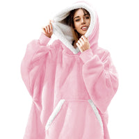 Frau in rosa Oversize-Kuscheldecke mit Kapuze, weiches Fleece, gemütliche Kleidung.