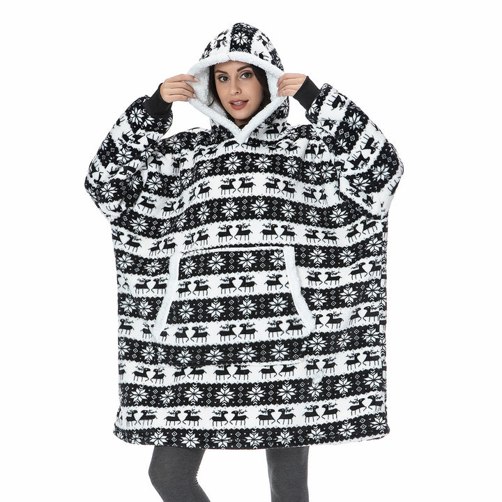 Frau in schwarz-weißem Oversize-Hoodie mit Rentiermuster, gemütliche Winterkleidung.