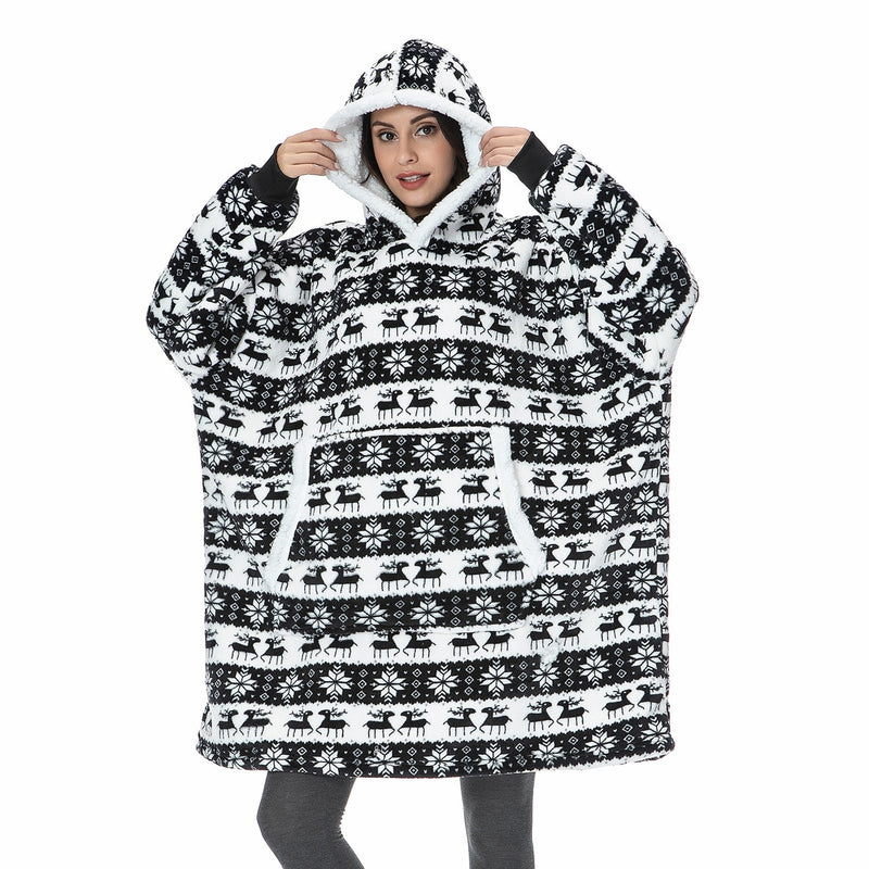 Frau in schwarz-weißem Oversize-Hoodie mit Rentiermuster, gemütliche Winterkleidung.