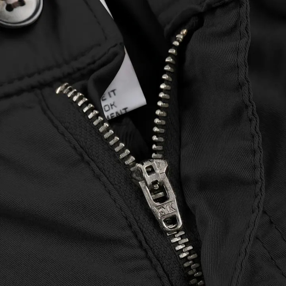 Schwarzer Reißverschluss an Jacke, Nahaufnahme, Metallzähne, robuste Verarbeitung.